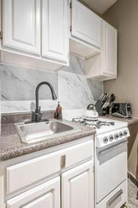 纽约Amazing 1Br in Manhattan的白色的厨房设有水槽和炉灶。