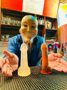 利马Hostel THAY83 Miraflores Lima的戴面具的人坐在桌子上,拿着瓶子