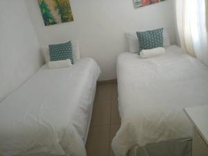 德班Manor house的配有白色床单和蓝色枕头的客房内的两张床