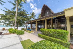 班邦宝TUI BLUE The Passage Samui Pool Villas with Private Beach Resort的海滩上的一座有树木和灌木的建筑