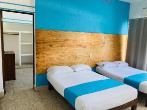 阿卡普尔科Hotel Lu Acapulco的配有两张床铺的蓝色墙壁和镜子