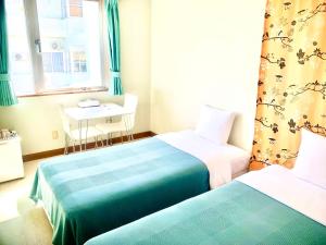 石垣岛石垣幸福假日酒店的配有桌子和窗户的客房内的两张床
