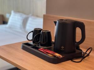 瓜拉丁加奴DJ Citi Plaza Hotel & Suites的桌上的盘子上有一个黑咖啡壶和两个肉桂棒
