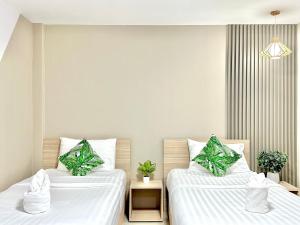 Ban Nong BuaThe Nine Place แจ้งสนิท的配有白色床单和植物的客房内的两张床