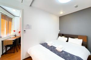 东京Uhome Mitomi Home 3F的卧室配有白色的床和书桌