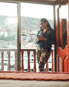 阿亚库乔Altipacha Ayacucho Hotel的站在阳台上看手机的女人