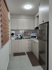 TranquerahThe Quartz 3 Bedroom Apartment with fully furnish and fully aircond, infinity pool, Corner lot with seaview and city view centre of malacca city的厨房配有白色橱柜和不锈钢冰箱