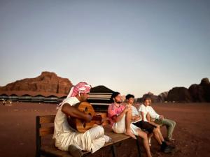 瓦迪拉姆Desert Bird Camp的一群人坐在沙漠的长凳上