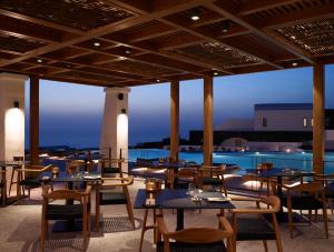 伊亚Santo Pure Oia Suites & Villas的一间带桌椅的餐厅和一个游泳池