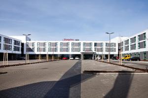 哈尔伯格摩斯Hampton by Hilton Munich Airport South的一座白色的大建筑,前面设有停车场