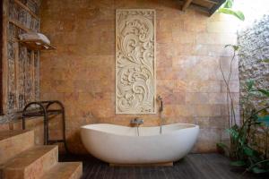 乌布Ubud Lestari Villa的带浴缸的浴室和砖墙