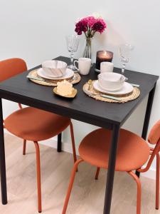 蒂尔WellnessStudioTiel的一张黑色餐桌,配有两把橙色椅子和一张黑桌子
