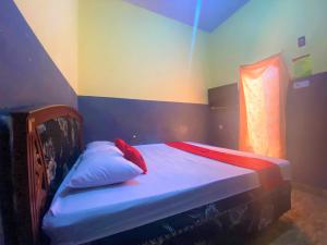 PalopoRedDoorz @ Wisma Sentosa Palopo的小卧室配有带白色床单和红色枕头的床