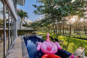 岘港Ocean Beach Villas Danang的一座游泳池,在院子里放着粉红色充气猪