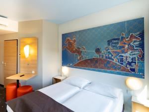 马格德堡B&B HOTEL Magdeburg-City的卧室配有一张床,墙上挂有绘画作品