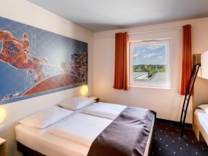 马格德堡B&B HOTEL Magdeburg-City的酒店客房设有两张床和窗户。