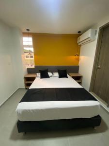 麦德林HOTEL ESTADIO DORADO的一间卧室设有一张黄色墙壁的大床