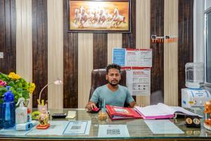 PhundardihHotel Welcome Sri Vip Road Raipur的坐在办公室桌子上的男人