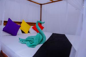 米瑞莎Sajana Ocean Hill的一只绿色的玩具恐龙坐在床上,床上有色彩缤纷的枕头