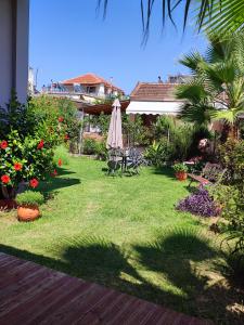 沃尼扎Maria's Paradise的一个带遮阳伞、椅子和鲜花的庭院