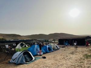 米茨佩·拉蒙חאן נחל חווה Han Nahal Hava的一群人站在沙漠中的帐篷