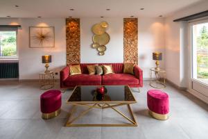 StaffelfeldenGîte au coeur de l'Alsace Maison Gatsby的客厅配有红色沙发和粉红色凳子