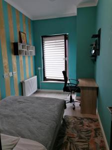 克卢日-纳波卡Queency Apartament cu gradina și parcare gratuita的一间卧室配有一张床、一张书桌和一个窗户。