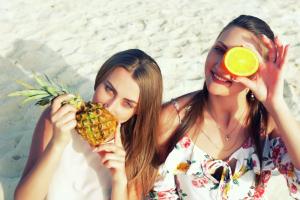 索瓦马希尔顿酒店死海度假村及Spa的两个在海滩上拿着 ⁇ 萝和橙子的女人