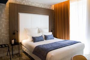 格勒诺布尔Le Grand Hôtel Grenoble, BW Premier Collection by Best Western的一间卧室配有一张大床和两个蓝色枕头