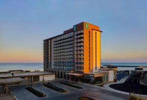 弗吉尼亚海滩Embassy Suites By Hilton Virginia Beach Oceanfront Resort的一座高大的橙色建筑,背景是大海