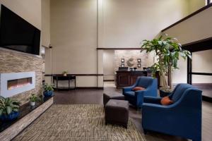 米德韦Comfort Inn & Suites Midway - Tallahassee West的大堂设有2把蓝色椅子和壁炉