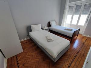 阿马多拉Lisbon traditional T2 with balcony in Damaia, Lisbon的铺有木地板的小客房内的两张床