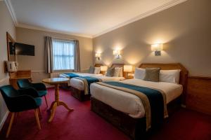 都柏林哈考特酒店的酒店客房,配有两张床和椅子