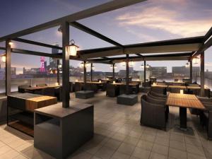 大阪Nest&Rise Osaka Namba Hotel的屋顶酒吧设有桌椅,享有城市美景