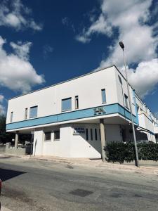 阿尔贝罗贝洛阿洛尼酒店的白色的建筑,上面有蓝色条纹