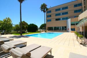 莱萨·达·帕尔梅拉TRYP by Wyndham Porto Expo Hotel的一座带躺椅的游泳池和一座建筑