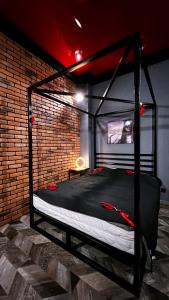 罗兹BDSM Red Room Apartment的砖墙间一张黑色的床