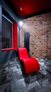 罗兹BDSM Red Room Apartment的砖墙房间里一张红椅