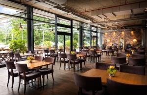 柏林HOTEL BERLIN KÖPENICK by Leonardo Hotels的餐厅设有木桌、椅子和窗户。