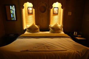 斋沙默尔Hotel Navodaya Jaisalmer的卧室配有一张带白色床单和枕头的大床。