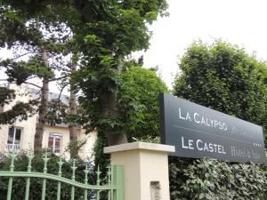 卡布尔Le Castel Cabourg hôtel & SPA- Restaurant La Calypso的建筑前的标志,带有栅栏