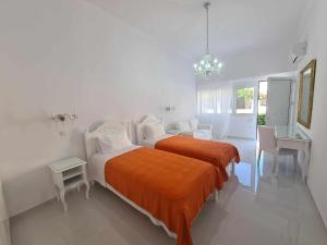 斯巴达NN Rooms and Suites near Athens Airport的白色卧室配有带橙色毯子的床