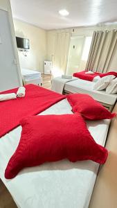 佩尼亚Pousada Helena的一间卧室配有两张带红色枕头的床。