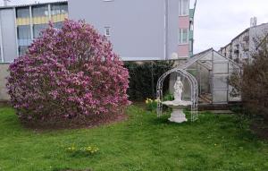 采尔特韦格Ring Gasthaus的一座雕像,位于一个布满紫色花的灌木丛旁