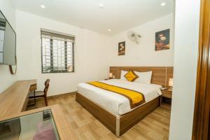 Ðộng HỏiSonne Hotel Quang Binh的一间卧室配有一张床、一张书桌和一个窗户。
