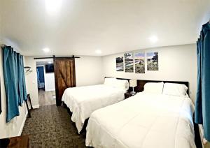 萨拉托加Snowy Mountain Inn的两张位于酒店客房的床,配有蓝色窗帘