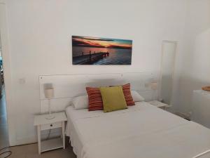 塞维利亚Casa Oliva 52的白色卧室配有一张床,墙上挂着一幅画