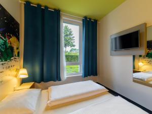 鲁尔河畔米尔海姆鲁尔河畔米尔海姆住宿加早餐酒店的一间卧室设有一张床、一台电视和一个窗口。