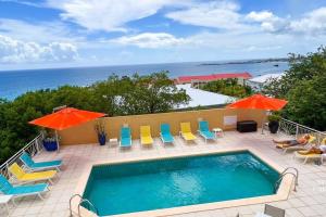 辛普森湾Villa Sea Forever @ Pelican Key - Paradise Awaits!的一个带椅子和遮阳伞的游泳池以及大海