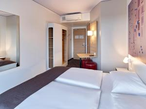 特罗斯多夫B&B Hotel Köln-Troisdorf的配有一张床和一张书桌的酒店客房